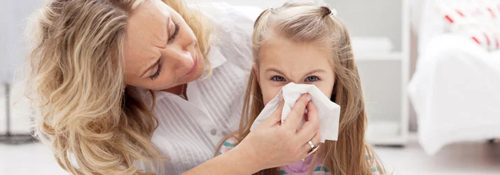 Chiropractic Livonia MI Allergies A mother holding a tissue to a young girls nose.
