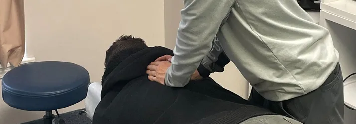 A chiropractor performing an upper back adjustment.