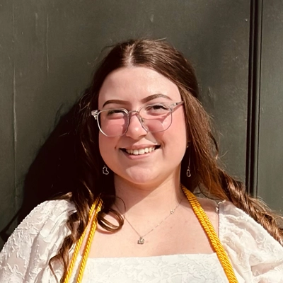 Office manager, Kursten, smiling in front of wall.