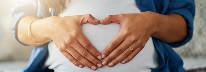 Chiropractic Livonia MI Pregnancy A pregnant woman holding her hands in a heart shape over her belly.